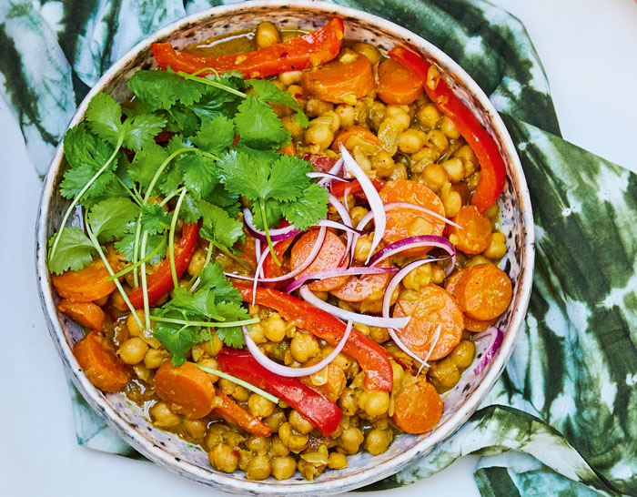 Spicy chickpea and coconut curry garnished with fresh coriander and red onion. Recipe from The Imperfect Nutritionist.